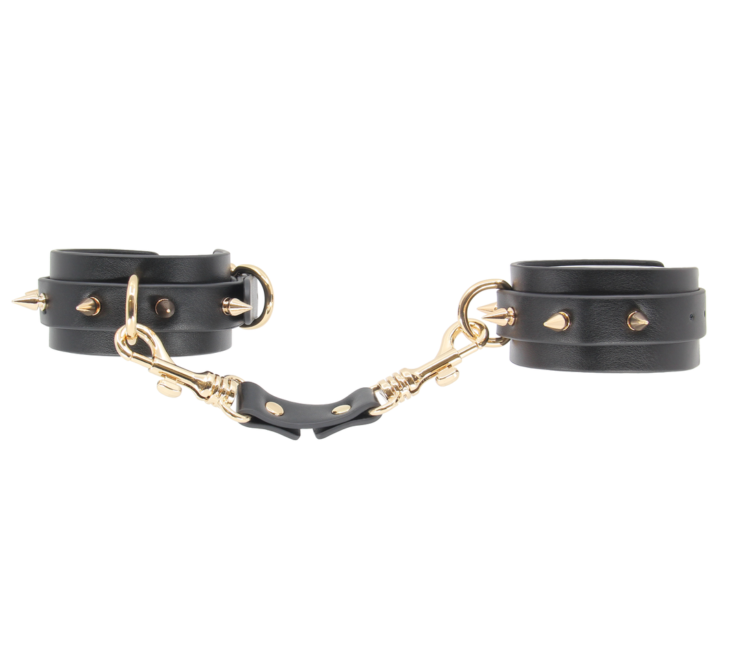 Spiked wrist cuffs close-up - premium leather construction with gold hardware and metal spikes